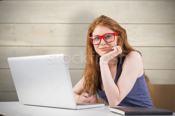 Stock photo: Composite image of pretty redhead working on laptop