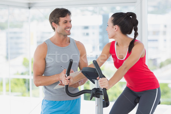 Stock photo: Woman with male instructor working out at spinning class