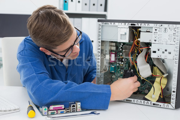 Souriant technicien travail brisé ordinateur bureau [[stock_photo]] © wavebreak_media