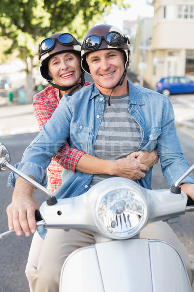 Stock photo: Happy mature couple riding a scooter in the city