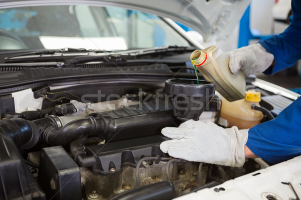 Stock photo: Mechanic pouring oil into car