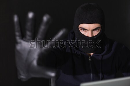 Hacker in balaclava gesturing and using laptop Stock photo © wavebreak_media