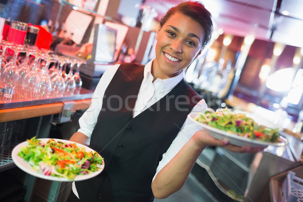 Stock photo: Pretty barmaid holding plates of salads