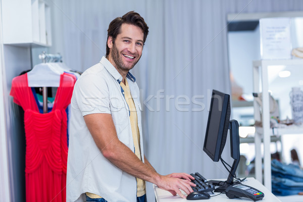 Souriant caissier tapant portrait vêtements magasin [[stock_photo]] © wavebreak_media