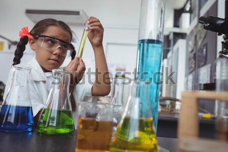 Stock photo: Flasks of chemicals on desk with elementary student using microscope in background