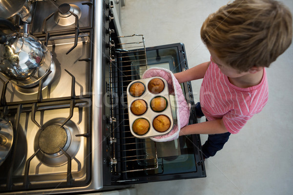 Boy holding muffin tin by oven Stock photo © wavebreak_media