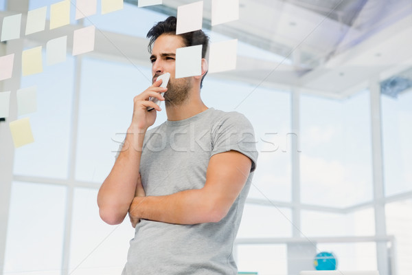 Stock photo: Thoughtful man looking at sticky notes on window