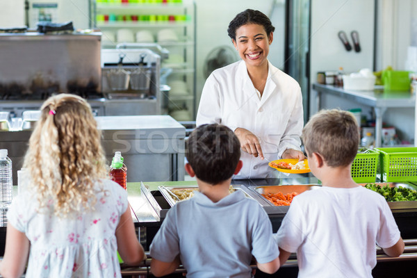 Cheerful woman serving food to schoolchildren  Stock photo © wavebreak_media