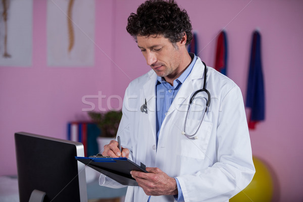 Physiotherapist writing on clipboard Stock photo © wavebreak_media