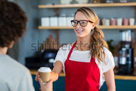 Smiling waitress serving a coffee to customer at counter in cafÃ© Stock photo © wavebreak_media