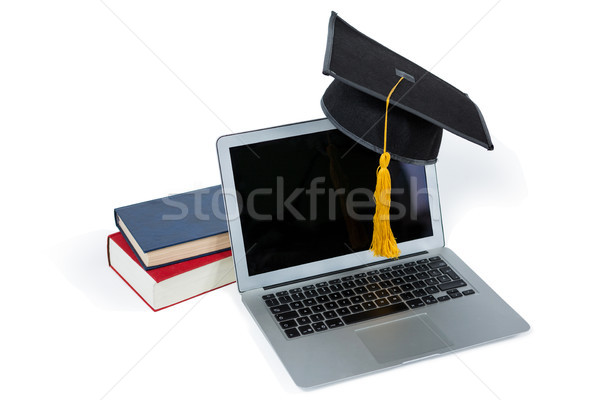 Stock photo: Laptop with mortarboard and books