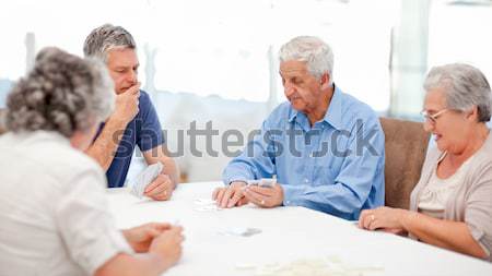 Stock photo: Retired people playing cards together at home