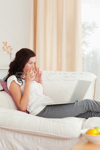 Surprised woman with a notebook in her livingroom Stock photo © wavebreak_media