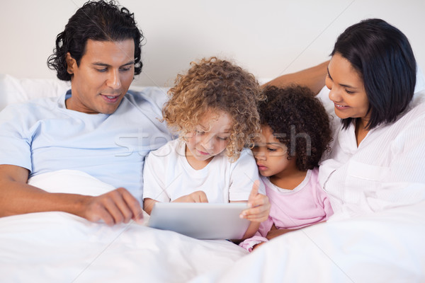 [[stock_photo]]: Jeunes · famille · séance · lit · comprimé · ordinateur