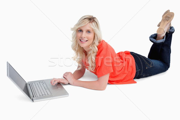 Femme blonde souriant couché jambes croisées portable technologie [[stock_photo]] © wavebreak_media