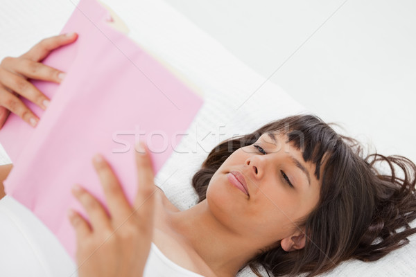 Stock photo: Angle shot of a young woman reading a book in her bed