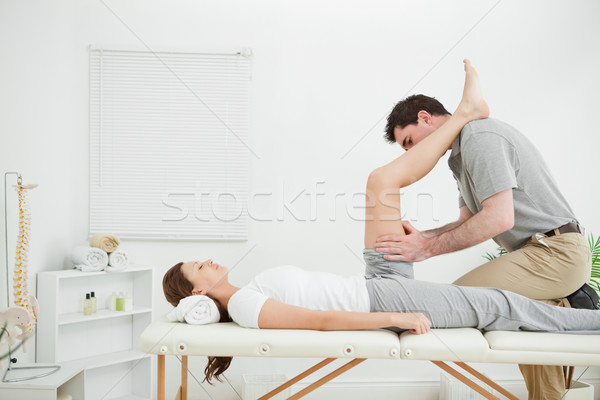 Doctor examining the thigh of a woman while putting her foot on his shoulder indoors Stock photo © wavebreak_media