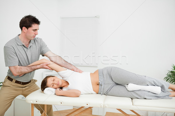 Chiropractor stretching the arm of his patient while holding it in a room Stock photo © wavebreak_media