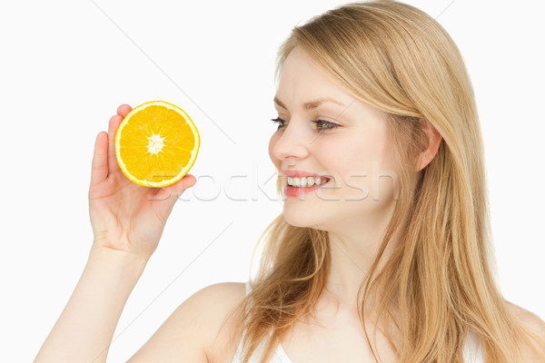 Joyful woman presenting an orange while looking at it against white background Stock photo © wavebreak_media