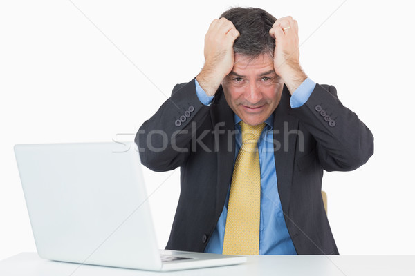 Troubled man sitting at his desk with a laptop on a white background Stock photo © wavebreak_media