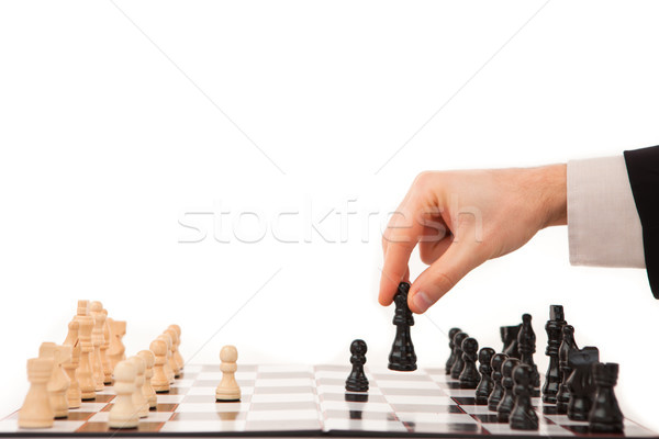 Hand moving a black chessman against white background Stock photo © wavebreak_media