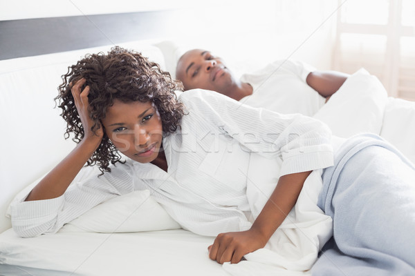 Annoyed woman lying in bed with boyfriend Stock photo © wavebreak_media