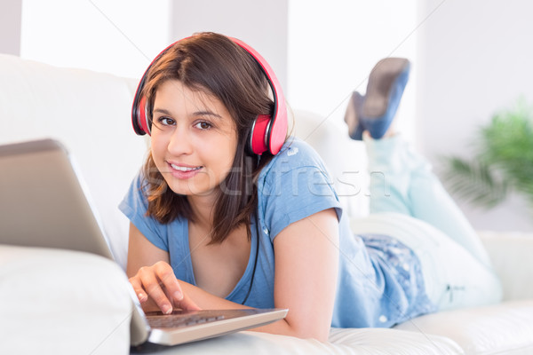 Pretty brunette using laptop listening to music on the couch Stock photo © wavebreak_media