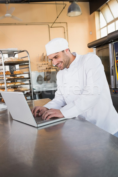 Zâmbitor brutar folosind laptop bucătărie brutărie afaceri Imagine de stoc © wavebreak_media
