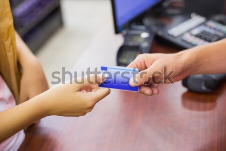 Stock photo: Smiling woman at cash register paying with credit card