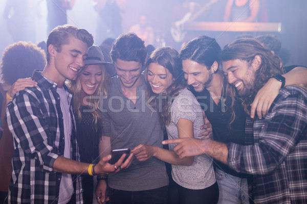 Smiling friends looking at smart phone in nightclub Stock photo © wavebreak_media