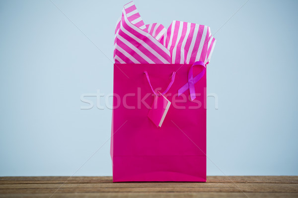 Close-up of vibrant pink Breast Cancer Awareness ribbon on shopping bag over wooden table Stock photo © wavebreak_media