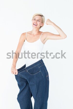 Stock photo: Cute woman wearing to big jeans in a studio