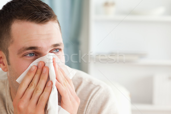 Sick man blowing his nose in his living room Stock photo © wavebreak_media
