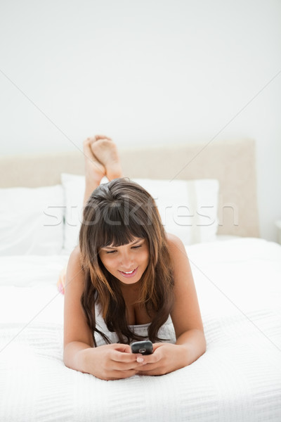 Sorridente mulher jovem celular cama leitura branco Foto stock © wavebreak_media