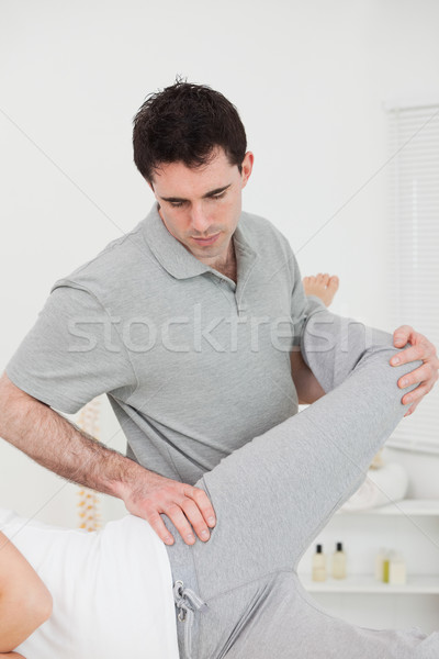 Physiotherapist standing behind a woman while stretching her leg in a room Stock photo © wavebreak_media