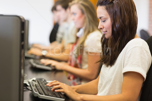 Stock photo: Woman looking at the keyboard typing in computer class in college