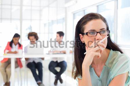 Attractive casual businesswoman holding pencil focusing Stock photo © wavebreak_media