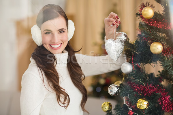 Smiling brunette holding heart near a christmas tree Stock photo © wavebreak_media