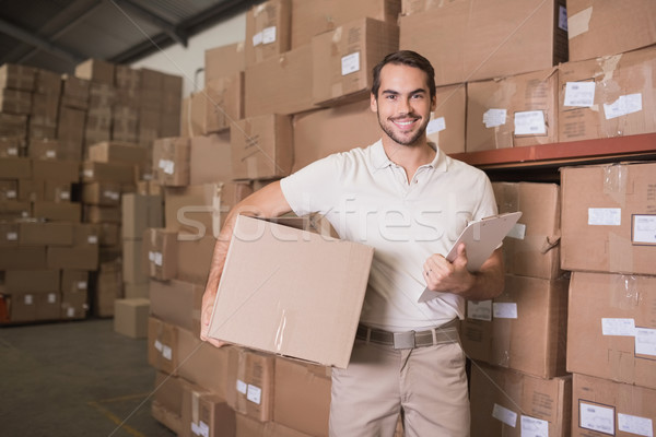 Delivery man with box and clipboard in warehouse Stock photo © wavebreak_media