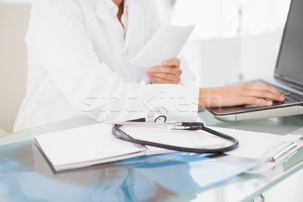 Stok fotoğraf: Doktor · yazarak · dizüstü · bilgisayar · stetoskop · kadın