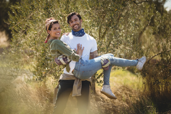 Smiling young man carrying girlfriend by trees at farm Stock photo © wavebreak_media