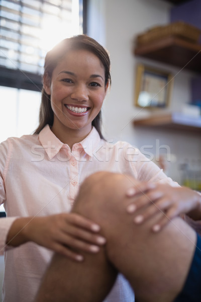 Portrait of smiling female therapist examining knee with senior male patient Stock photo © wavebreak_media