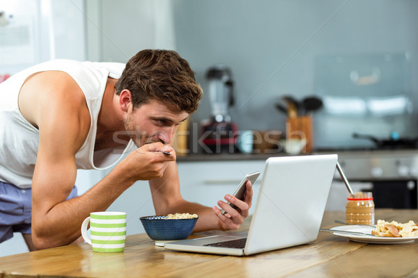 Man having breakfast while using mobile phone in kitchen Stock photo © wavebreak_media
