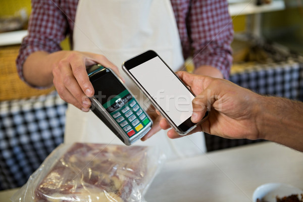 Mid section of man paying through nfc technology at counter Stock photo © wavebreak_media