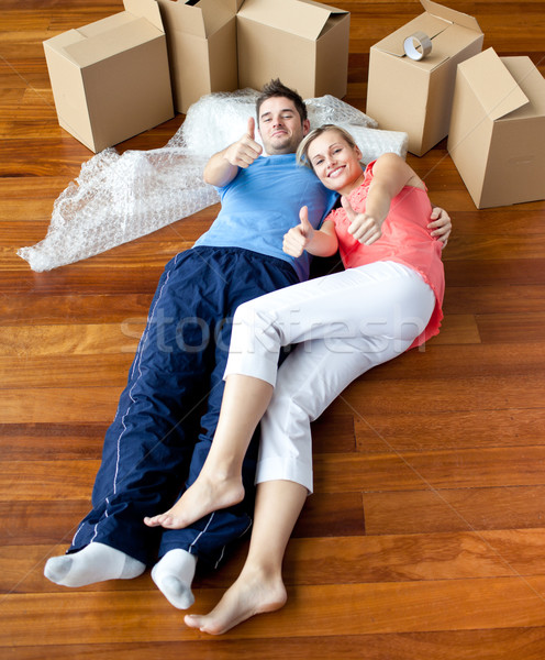  happy couple lying on the floor in their new house doing thumbs-up to the camera Stock photo © wavebreak_media