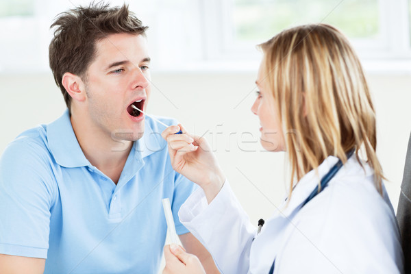 Caucasian female doctor taking a saliva sample of a male patient using cotton-bud standing in her of Stock photo © wavebreak_media