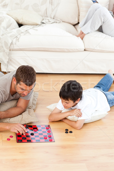 Stock photo: Father and son playing checkers together lying on the floor