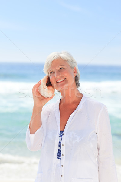 Mujer madura escuchar Shell mujer playa nina Foto stock © wavebreak_media