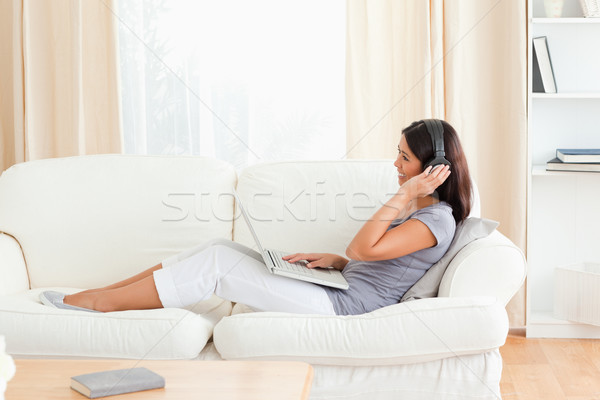 улыбающаяся женщина сидят Жилье диван компьютер Сток-фото © wavebreak_media