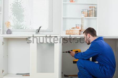 Good looking handyman fixing a door in a kitchen Stock photo © wavebreak_media